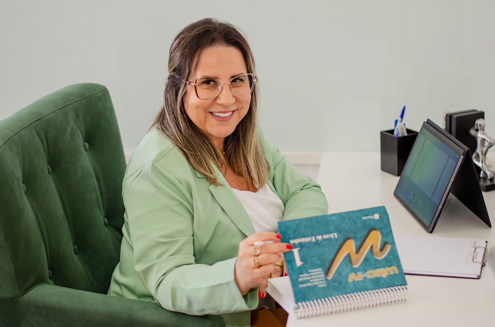 Elisangela Jacobs com o material da avaliação neuropsicológica WISC-IV, sorrindo no consultório
