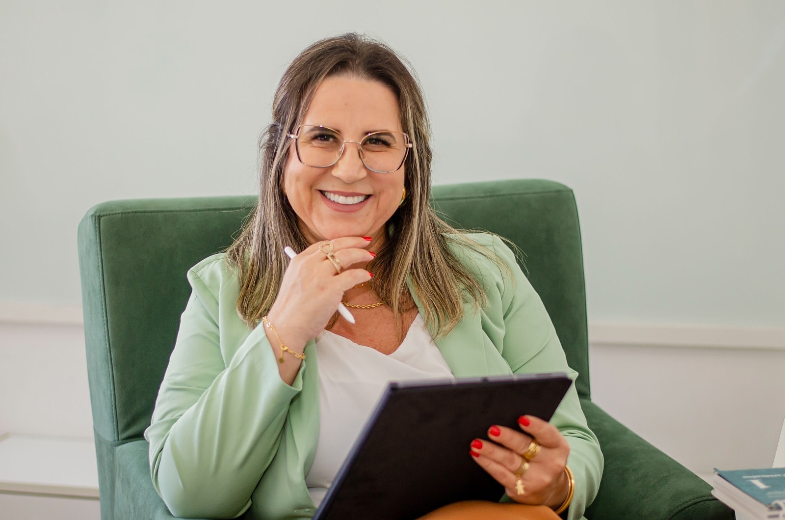 Elisangela Jacobs, psicóloga, sorrindo sentada no consultório